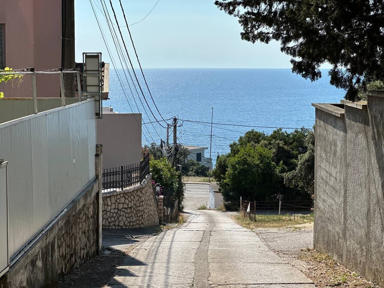 Une rue étroite qui mène à un plan d’eau, bordée de bâtiments des deux côtés et offrant une vue dégagée sur la mer.