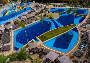 A large outdoor swimming pool area with multiple sections, lounge chairs, and palm trees. - SOLAR DAS AGUAS PARK RESORT - OLIMPIA (Olímpia)
