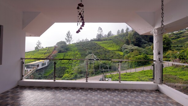 Un balcón con vistas a un paisaje verde y un edificio blanco.
