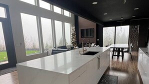 Una cocina moderna con una isla grande, suelo de madera y ventanas amplias.