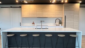 Una cocina moderna con una isla central, taburetes de bar y armarios de madera.