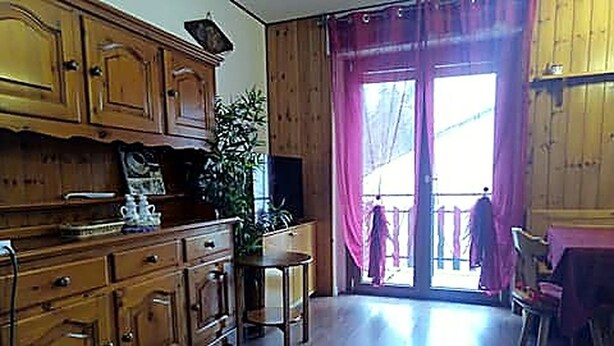 A wooden kitchen with cabinets, a dining table, and chairs. - Casa del sole Oulx vicino alle piste da sci (Oulx)