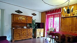 A spacious living room with wooden cabinets, a dining table, and a chandelier. - Casa del sole Oulx vicino alle piste da sci (Oulx)