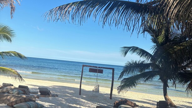 A beach with lounge chairs and a signpost. - 2-bedroom apartment in phenomenal Tulum with AC and fitness room (Tulum)