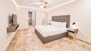A modern bedroom with a large bed, a ceiling fan, a TV, and a nightstand. - 2-bedroom apartment in phenomenal Tulum with AC and fitness room (Tulum)
