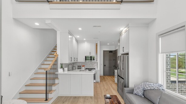 A modern kitchen with white cabinetry, a central island, and a built-in oven. - New Luxury Condo in The Heart of Nolensville (Nolensville)