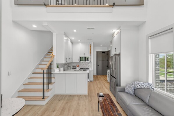 A modern kitchen with white cabinetry, a central island, and a built-in oven. - New Luxury Condo in The Heart of Nolensville (Nolensville)