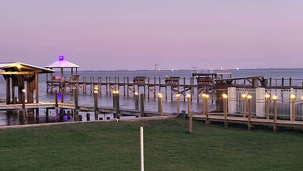 Une jetée bordant le rivage, dotée de structures en bois et d’espaces aménagés avec des sièges, le tout relié par des passerelles.