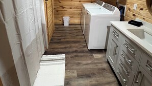 Una cocina compacta con paredes de madera, lavadora, lavamanos y armarios.