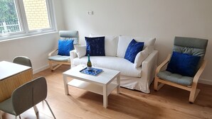 Moderni olohuone, jossa on valkoinen sohva, kaksi nojatuolia, sohvapöytä ja ruokapöytä.