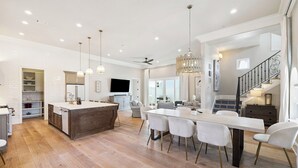 Una cocina amplia con una isla central, piso de madera e iluminación colgante.