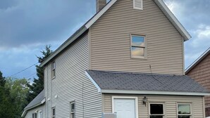 A two-story house with a gabled roof, a front door, and a small porch. - Cozy 2-bedroom cottage in historic Calumet (calumet)