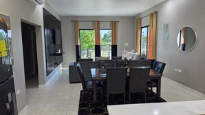 Uma sala de jantar moderna com uma mesa grande, cadeiras e um tapete preto.