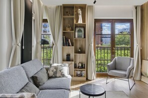A living room with a grey sofa, a black coffee table, a wooden bookshelf, and a grey armchair. - Luxury 2-room apartment in Praga-Północ Port Praski (Warszawa)