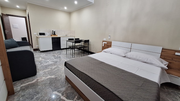 A bedroom with a bed, a desk, and a kitchenette. - Arte Mia suite (Reggio Calabria)