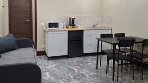 A compact living space with a kitchenette, a dining area, and a sofa. - Arte Mia suite (Reggio Calabria)