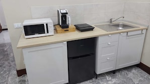 A compact kitchen with a microwave, coffee maker, and induction cooktop on a light-colored countertop. - Arte Mia suite (Reggio Calabria)