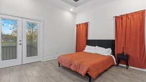 Ein Schlafzimmer mit Bett, Nachttisch und einer Schiebetür zu einem Außenbereich.