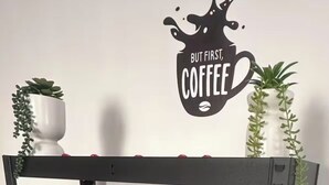 Een zwarte metalen plankunit met een koffiezetapparaat, een mand en decoratieve items.
