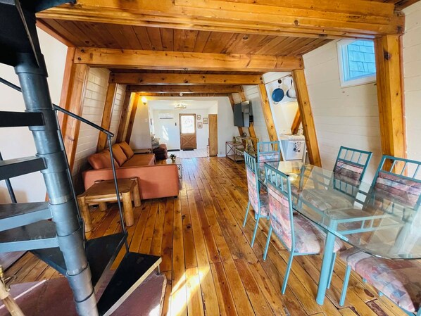 Un acogedor loft con suelo de madera, una mesa de comedor de vidrio y un sofá.