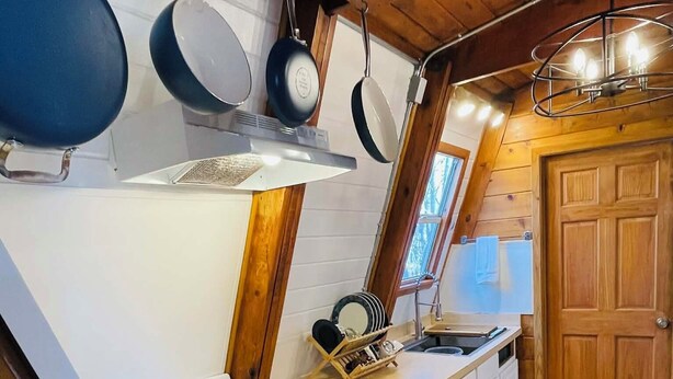 Een kleine keuken met een fornuis, witte kastjes en een houten plafond.