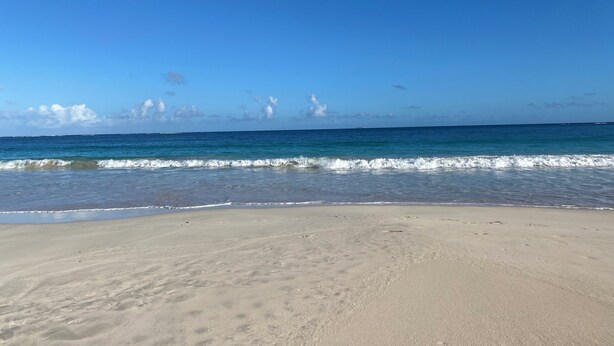 Een strand met heldere lucht en rustige golven.