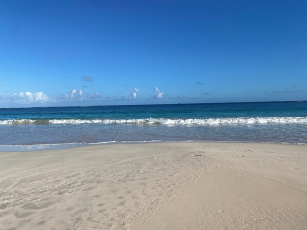Una playa con cielos despejados y olas tranquilas.