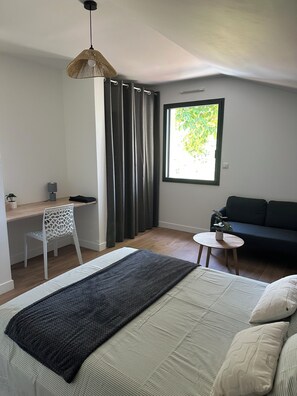 A bedroom with a bed, a desk, a chair, a sofa, a window, and a hanging light fixture. - New house 155 m² /Seaside on foot (100 m)/4 beautiful bedrooms, garden, parking (Saint-Brevin-les-Pins)