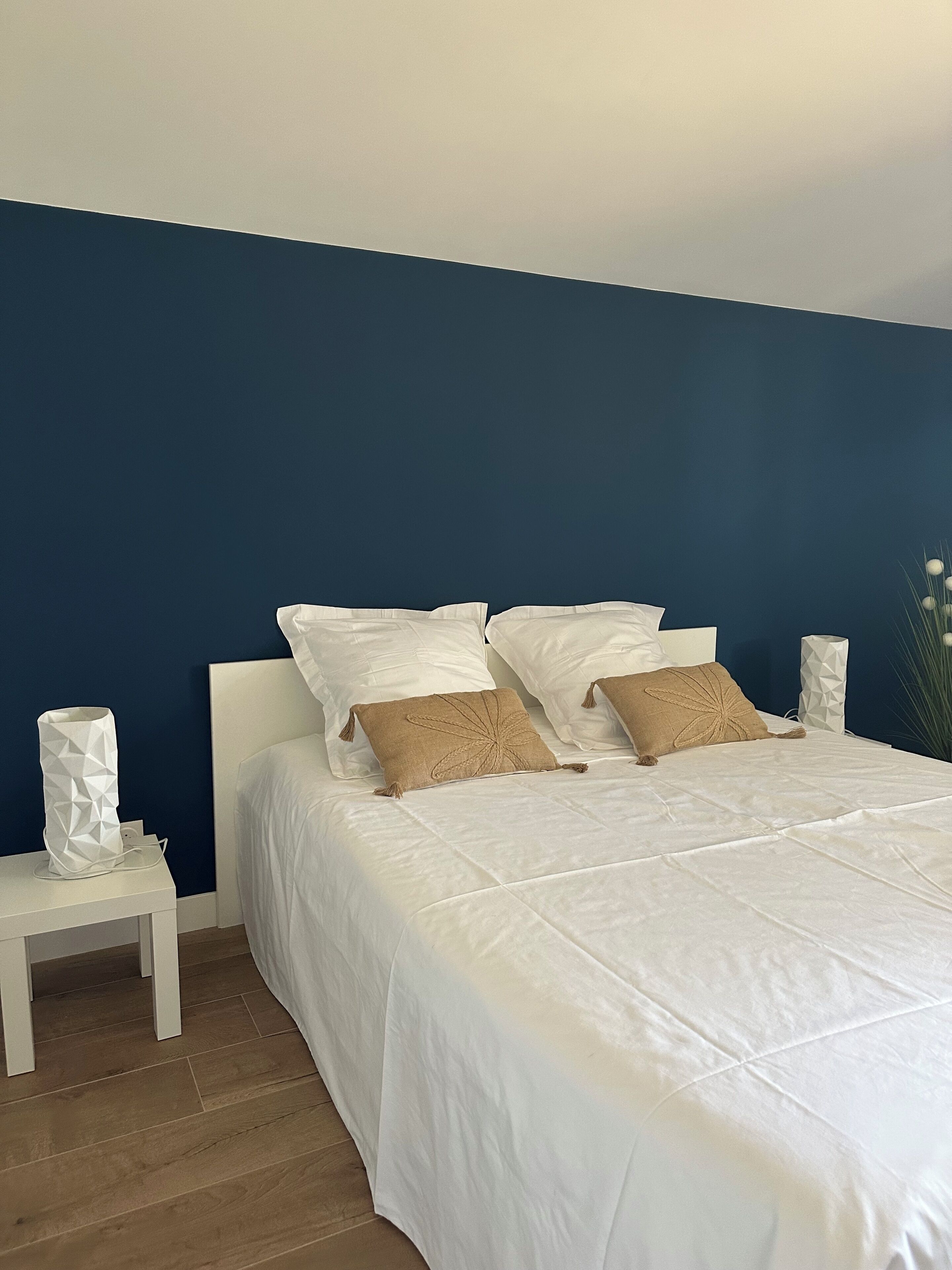 A bedroom with a bed, pillows, a nightstand, and a wall unit.