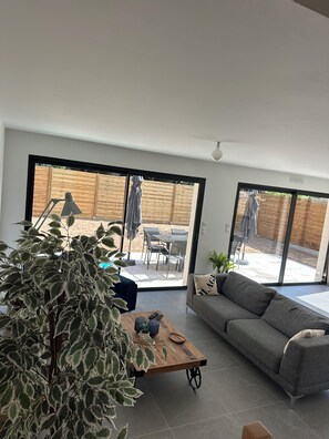 A modern living room with a grey sofa, a wooden coffee table, and a large plant. - New house 155 m² /Seaside on foot (100 m)/4 beautiful bedrooms, garden, parking (Saint-Brevin-les-Pins)