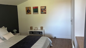 Un dormitorio con cama, mesitas de noche, lámpara colgante y decoración en la pared.