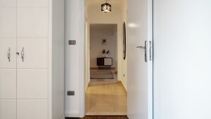 Un pasillo con suelo de madera que conduce a una habitación con cama y cómoda.