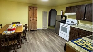 A kitchen with wooden cabinets, a stove, and a dining table with chairs.