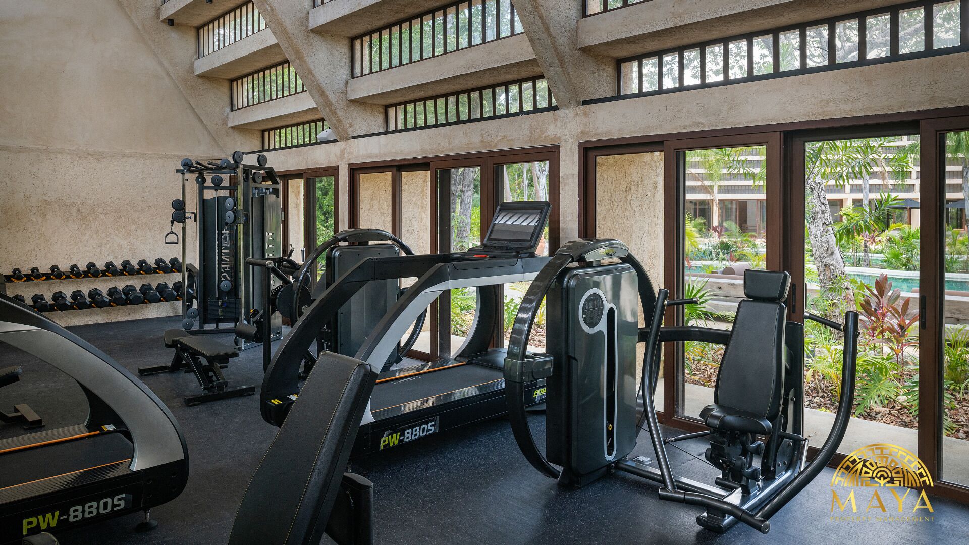 Ett gym med löpband, styrketräningsmaskiner och hantlar.