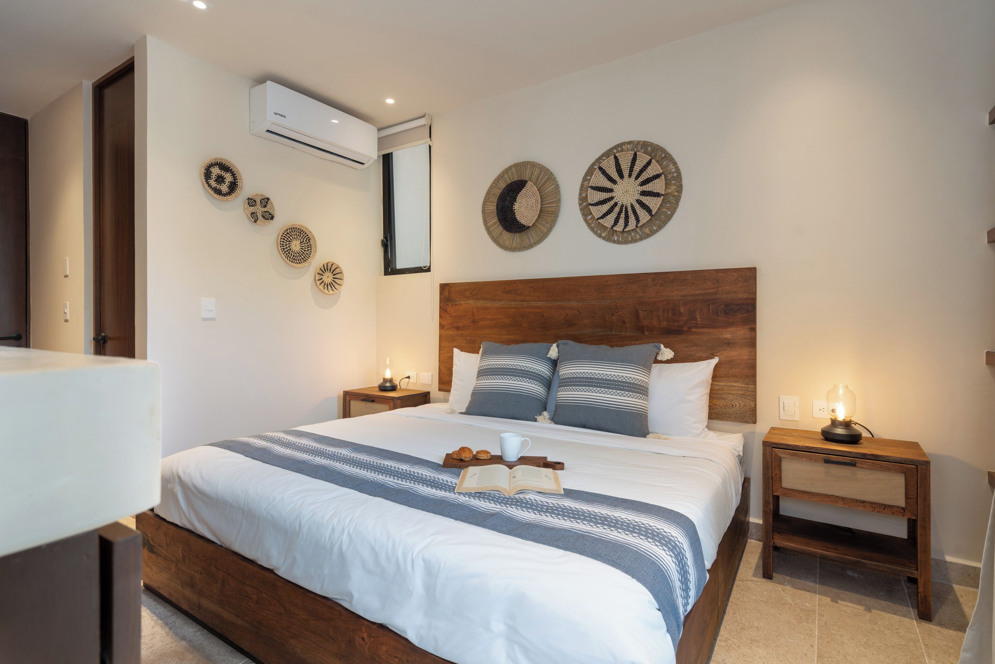 A neatly arranged bedroom with a wooden headboard, a bed with white bedding, decorative wall art, and bedside lamps.