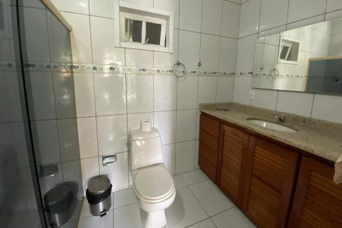 Une salle de bain avec des carreaux blancs, des toilettes, un lavabo et des meubles en bois.