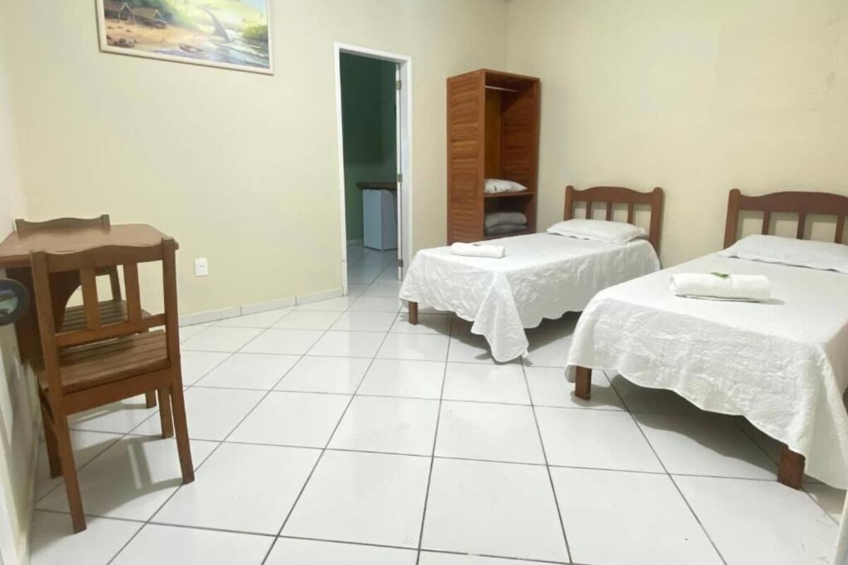 Une chambre avec deux lits, une armoire en bois, un bureau et une chaise.