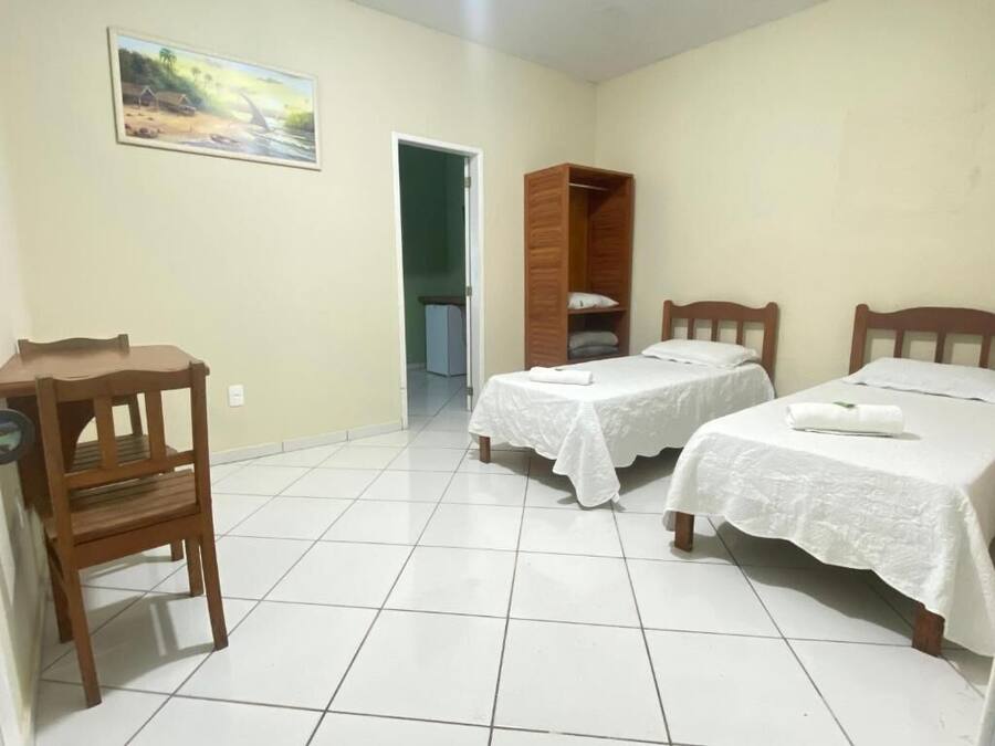 Un dormitorio con dos camas, un armario de madera, un escritorio y una silla.