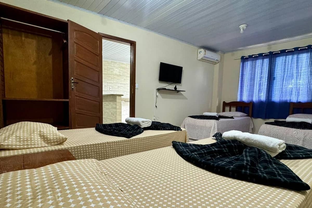 Une chambre d’hôtel avec deux lits, une télévision et une fenêtre avec des rideaux.