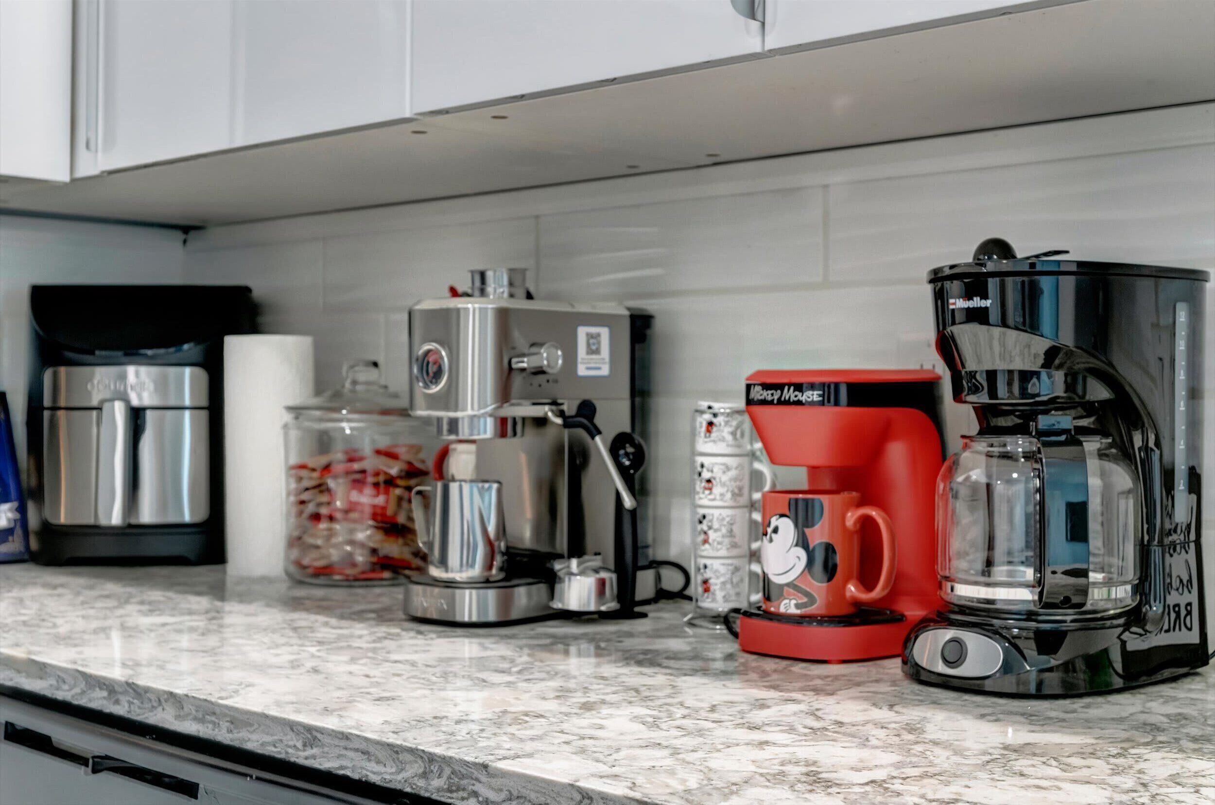 A kitchen with a coffee maker, a blender, and a jar of pasta.