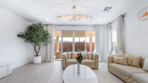 A modern living room with a large potted plant, two sofas, a coffee table, and a chandelier. - Resort-Style 4BR Home in Lake Las Vegas-Near Strip (Henderson)