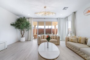 A modern living room with a large potted plant, two sofas, a coffee table, and a chandelier. - Resort-Style 4BR Home in Lake Las Vegas-Near Strip (Henderson)