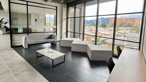 Ein modernes Wohnzimmer mit großem Fenster, einer Couch, einem Couchtisch und einem Essbereich.