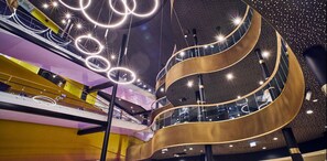 Een meerlaags atrium met een modern ontwerp, met een centrale spiraaltrap en verlichte, ronde lampen.