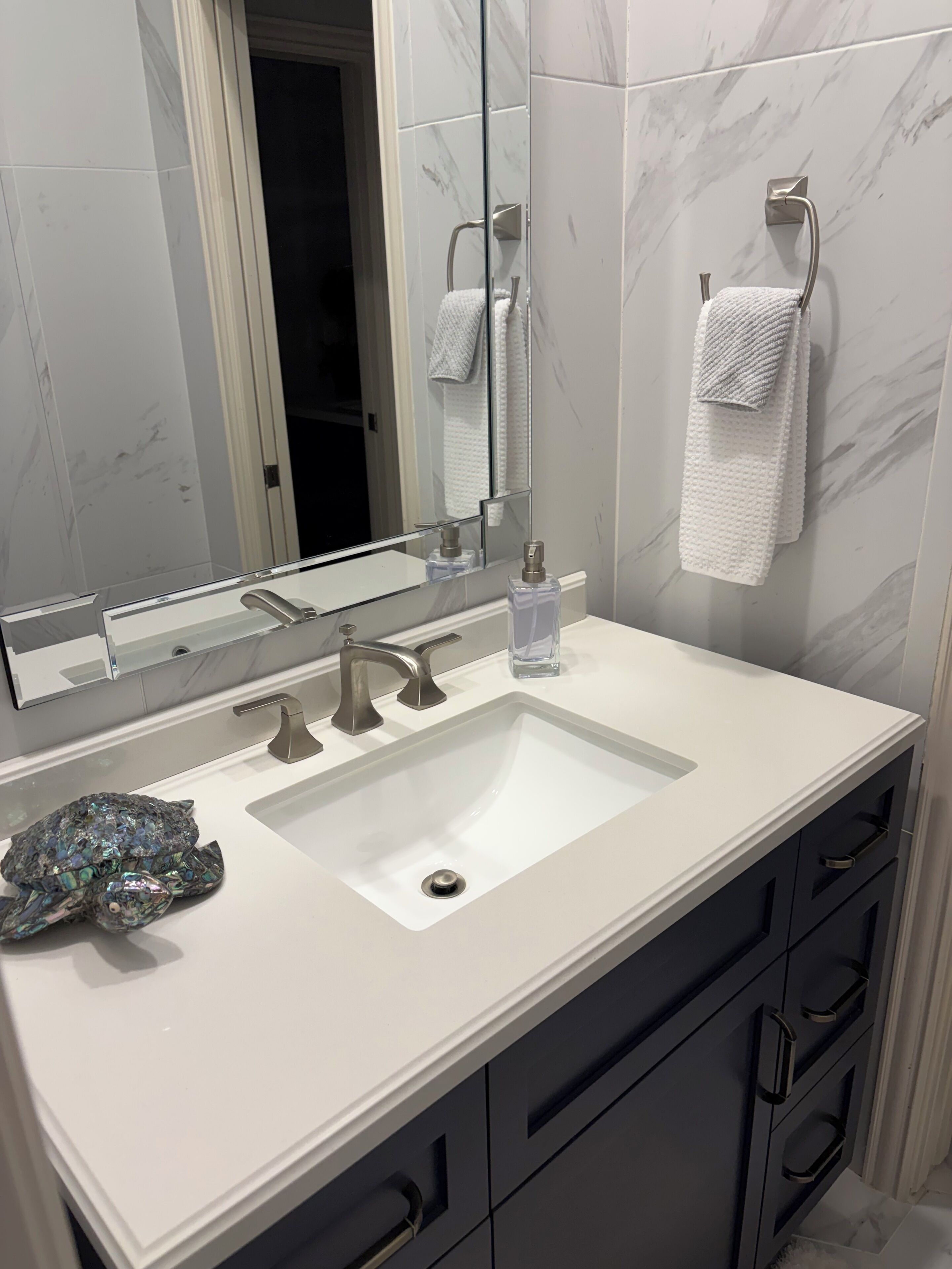 A bathroom with a white sink, two faucets, a mirror, and a towel rack.