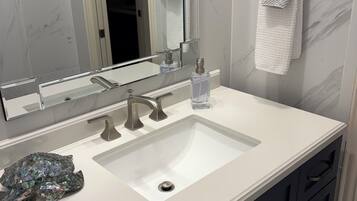 A bathroom with a white sink, two faucets, a mirror, and a towel rack.