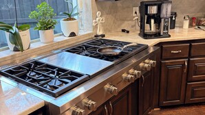 A kitchen with a stainless steel stove, wooden cabinets, and a coffee maker on the counter. - Cozy 1-bedroom bed & breakfast in charming Dallas with AC (Dallas)