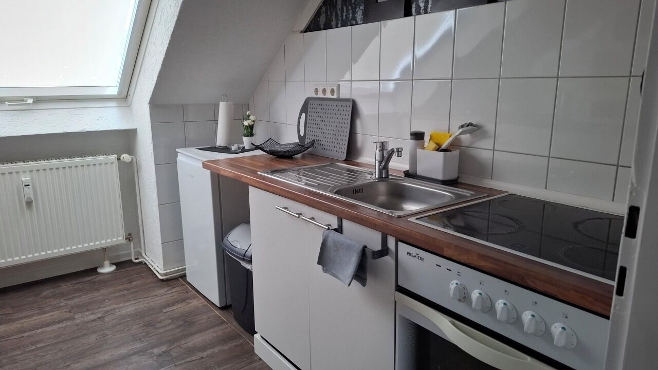 A compact kitchen with a built-in stove, a sink, and a small refrigerator.