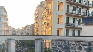 A rooftop terrace with tiled flooring, a stone wall, and a metal railing. - B&B Dimora delle Province (Catania)