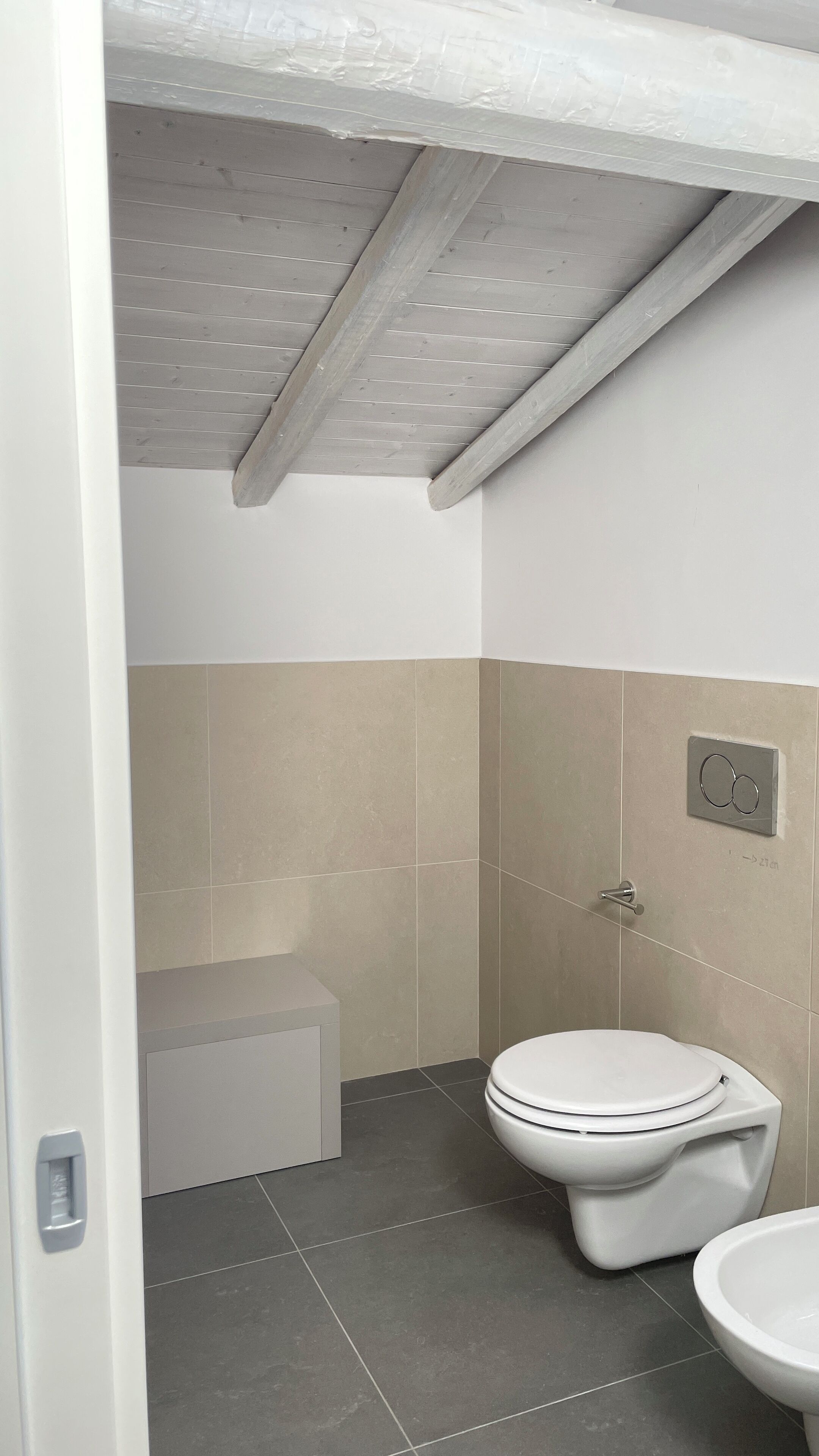 A small, modern bathroom with a toilet, bidet, and sink.